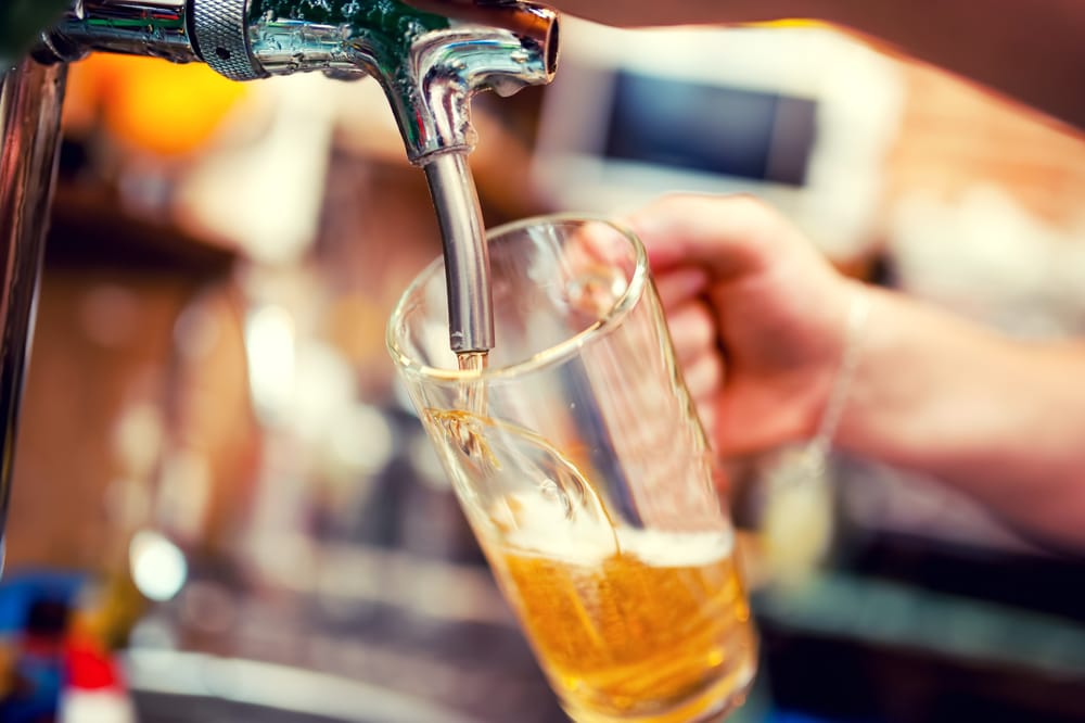 close-up of barman hand at beer tap pouring a draught lager beer